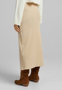 Beige ribbade stickade maxikjol som matchas med bruna mockaboots med klack; har en slim-fit silhuett och en texturerad tyg.