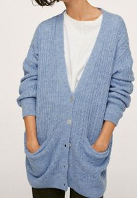 Cardigan bleu clair en tricot avec un motif texturé, devant ouvert, manches longues, deux poches avant et détails de boutons circulaires.