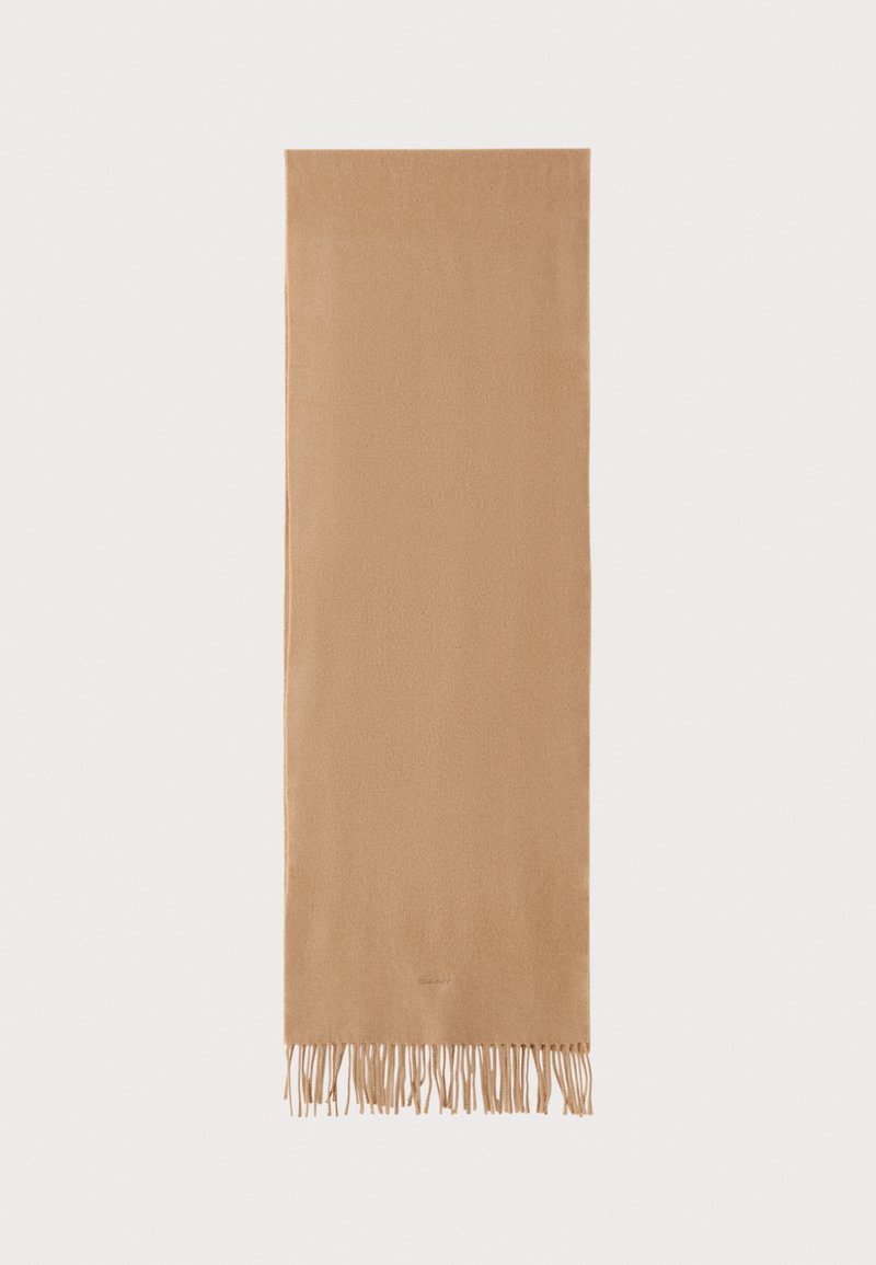 Soft, beige scarf made of a textured material, featuring fringe at the ends and a rectangular shape. Subtle branding at one side.