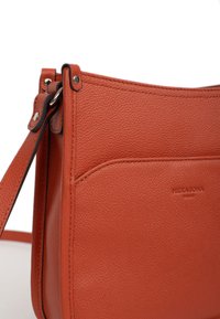 Borsa a spalla in pelle rossa con texture granulosa, caratterizzata da un design slanciato, tracolla regolabile e logo impresso di lato.
