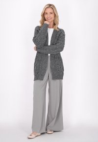 Cardigan gri tricotat cu un model texturat, design cu fața deschisă și mâneci lungi, asociat cu pantaloni largi gri deschis și balerini bej.