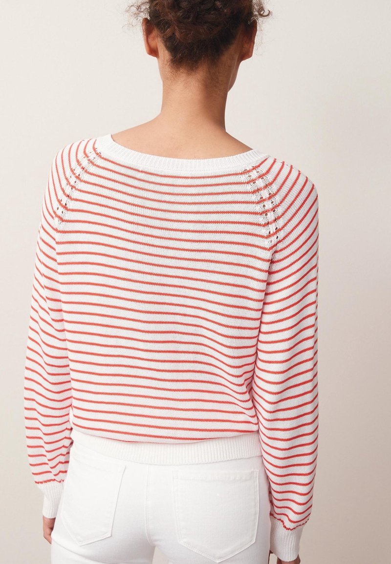 Pull rayé rouge et blanc avec un col rond, des poignets côtelés et un design légèrement court. Matière tricotée douce avec des détails de texture subtils.