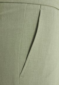 Světlá zelená tkanina s hladkým povrchem, která má jednu postranní kapsu a úhledné švy podél okrajů.