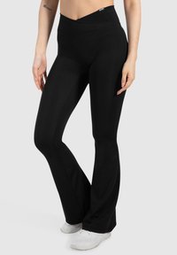 Zwarte flared leggings van rekbaar materiaal, met een hoge tailleband en een gladde textuur. Geschikt voor sportieve kleding.