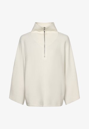 Off-white langærmet sweater med høj ribbet krave og en sølvfarvet lynlås foran, der går halvvejs ned over brystet.