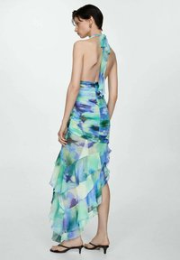 Ruched halter dress in blue and green watercolor pattern, with a backless design and layered ruffles, made of lightweight fabric.