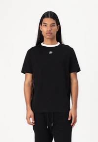 Svart t-shirt med vit ribbad krage och broderad logotyp på bröstet. Kort ärm, avslappnad passform, tillverkad av mjukt bomullsmaterial.