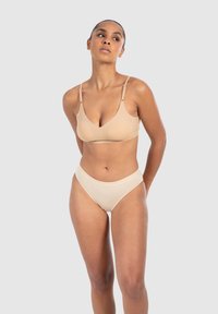 Bralette beige con spalline regolabili e finitura liscia abbinato a uno slip da bikini a vita alta con coste nello stesso colore.