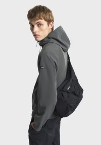 Grå hættejakke med tætsiddende pasform og elastiske manchetter, parret med en sort skuldertaske med et brandlogo. Glat tekstur og moderne design.