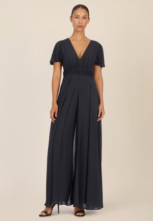 Navy blue jumpsuit with a deep V-neckline, short flutter sleeves, and pleated wide legs. Features a cinched waist and a flowy fabric.
