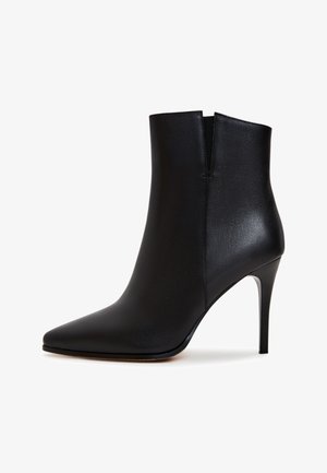 Mustat nahka nilkkakengät, joissa on sulavalinjainen muotoilu, terävä kärki ja korkea stiletto-korko. Ominaisuuksina minimalistinen leikkaus ilman näkyvää metalliosaa.