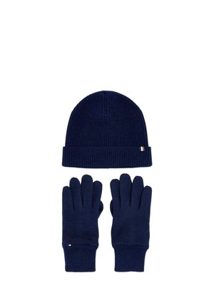 Navy blue knit hat with cuff and matching gloves with ribbed cuffs arranged on white background.