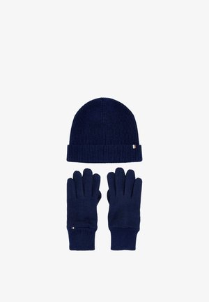 Navy blue knit hat with cuff and matching gloves with ribbed cuffs arranged on white background.