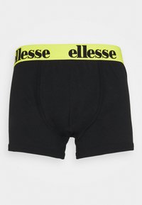 Svarta bomullboxershorts med ett brett, klart gult elastiskt midjeband som pryds av varumärket "ellesse" i svart.