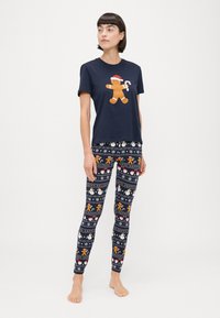 Conjunto de pijama azul marino que incluye una camiseta de manga corta con un gráfico de un hombre de jengibre y leggings estampados con diseños festivos de vacaciones.