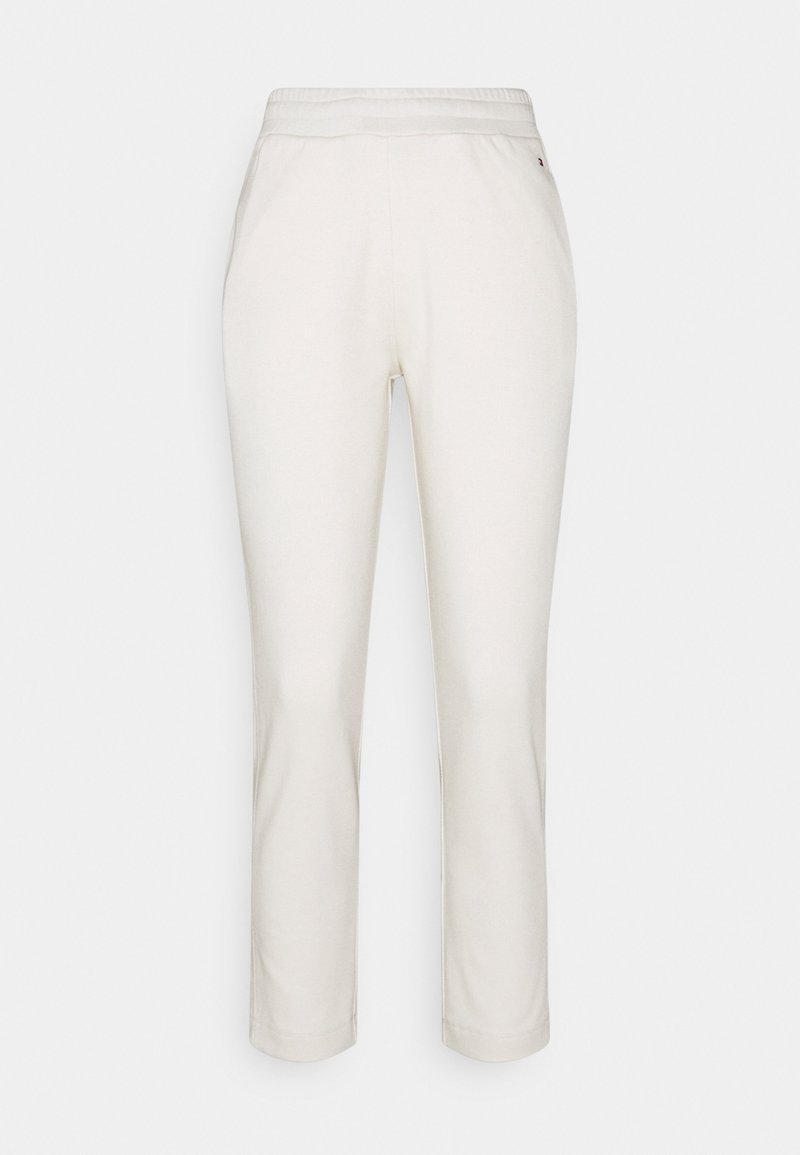 Białe spodnie o prostych nogawkach z elastyczną talią i kieszeniami po bokach, przedstawione na jasnym, jednolitym tle.