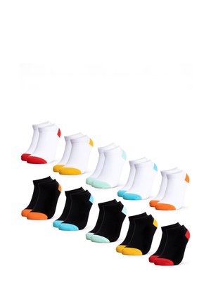 Beine mit schwarzen Sneakersocken mit roten Fersen und Zehen, vor einem schlichten weißen Hintergrund gezeigt.