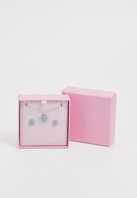 Silberne Halskette und passende Ohrringe mit hellblauen blütenförmigen Steinen, präsentiert in einer pinkfarbenen strukturierten Geschenkbox.