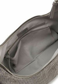 Interno della borsa grigia con texture intrecciata, dotato di zip, che presenta un ampio scomparto, una tasca con zip e una piccola tasca aperta per l'organizzazione.