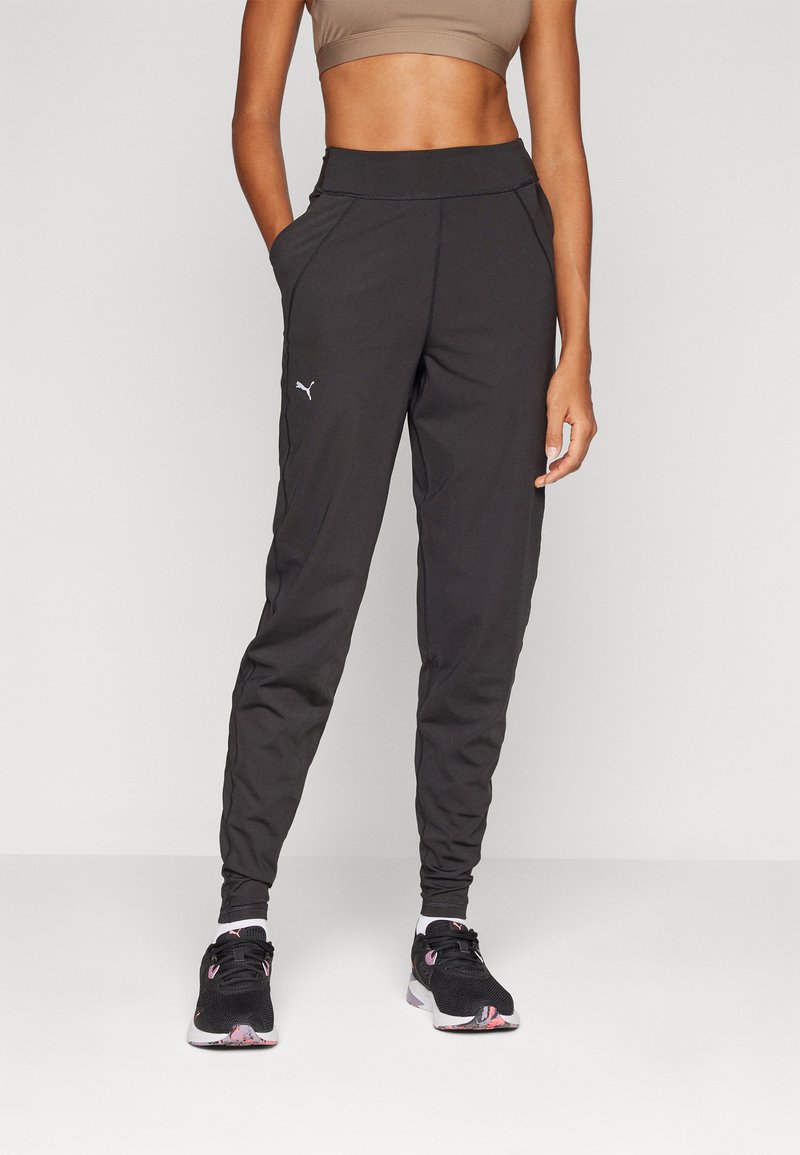 Schwarze Sporthose mit schmalem Schnitt, seitlichen Taschen, hohem Bund und einem kleinen weißen Logo am Oberschenkel.