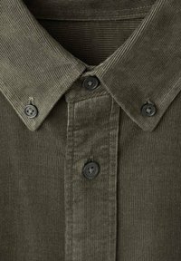 Camisa de pana color verde oliva con cuello abotonado, cinco botones negros y textura de canalé vertical.