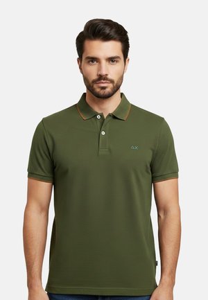 Uomo che indossa una polo aderente verde oliva a maniche corte, con due bottoni e un piccolo logo blu sul petto sinistro, su sfondo neutro.