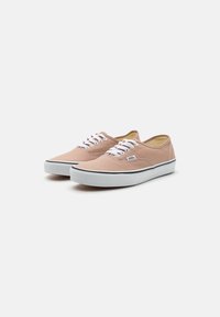 Canvas sneakers i en ljusrosa nyans med vita snören, vit gummisula och svart kant. Har en enkel design med rundad tå.