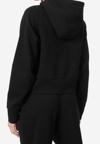 Sweat à capuche noir coupé court avec capuche, fabriqué en tissu doux. Comprend des poignets côtelés et un ourlet droit, avec un design épuré et des détails minimalistes.