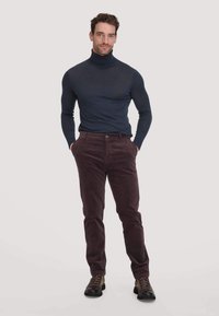 Marineblauwe coltrui gecombineerd met bordeauxrode corduroy broek en bruine veterschoenen. De outfit heeft een getailleerd ontwerp en een zachte structuur.