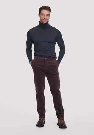 Marineblauwe coltrui gecombineerd met bordeauxrode corduroy broek en bruine veterschoenen. De outfit heeft een getailleerd ontwerp en een zachte structuur.