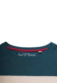 T-paita turkoosina, jossa on punainen kaulus ja vaalea vaakaraita. Pehmeää puuvillamateriaalia, jossa on näkyvät ompeleet ja etiketti, jossa lukee "Band of Rascals."