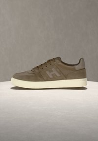 Baskets en cuir marron avec lacets et semelle blanche, vues de profil sur un fond neutre uni.