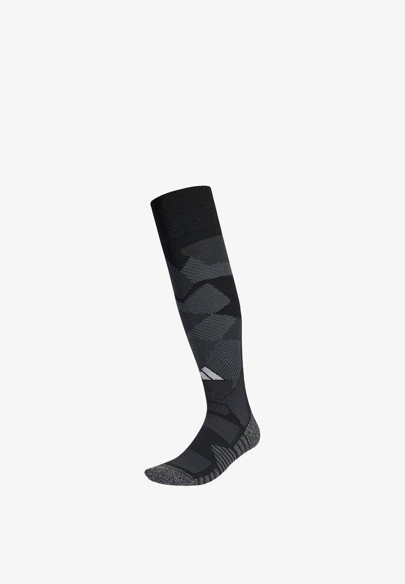 Chaussette de sport noire et grise haute jusqu'au genou avec des motifs géométriques et un logo blanc sur la partie inférieure du mollet.