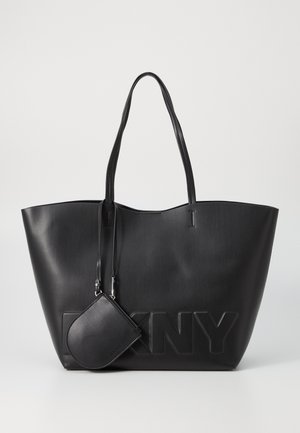 Black faux leather tote bag with high sides, embossed DKNY logo, and matching small zip pouch attached. Long, thin handles.