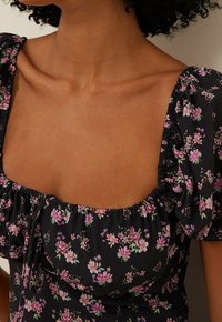 Černé květinové šaty s hranatým výstřihem, nabíranými rukávy a nařaseným živůtkem s malými růžovými a fialovými květinovými vzory.