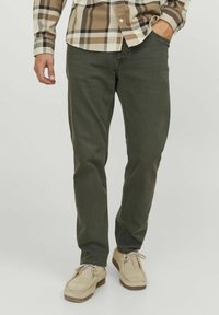 Pantalones verde oliva de corte ajustado, confeccionados en tela de mezcla de algodón. Presentan cinco bolsillos, lazos para cinturón y detalles de costura.