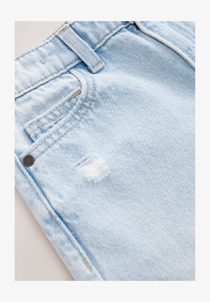 Jeans de mezclilla azul claro con textura arrugada, que cuentan con un bolsillo delantero, un pequeño desgarro en el muslo y un botón metálico marrón.