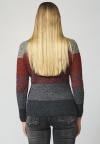 Pull en tricot avec des rayures horizontales rouges, grises et bleu foncé. Manches longues, texture côtelée et coupe décontractée avec un ourlet plongeant.