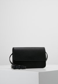 Czarna skórzana torebka na ramię z klapką, o prostokątnym kształcie i regulowanym paskiem. Gładka faktura, minimalistyczny design, bez widocznych elementów metalowych.