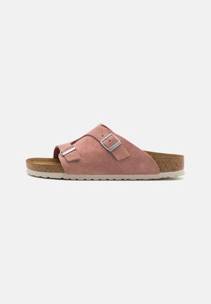 Sandal in suede rosa a slip-on con due cinturini regolabili con fibbie, sottopiede in sughero e suola in gomma bianca con texture a righe.