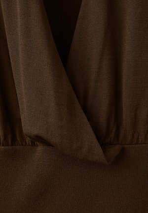 Ruskea kangas, jossa on pehmeä, teksturoitu viimeistely. Pääntiellä on laskostettu kuvio, ja vyötäröllä on joustava vyötärönauha, joka antaa rakenteellisen istuvuuden.