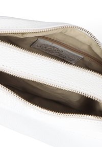 Borsa bianca in pelle con superficie texture, dotata di tre cerniere dorate e foderata in beige. Visibili due scomparti con cerniera.