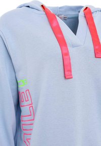 Hoodie bleu clair avec un décolleté en V profond, doté de cordons en satin rose et d'un texte vibrant en néon vert et rose sur la manche. Texture de tissu douce.