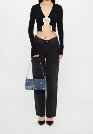 Sort cropped sweater med v-hals og unik udsnit, parret med mørk denim wide-leg jeans og en blå, sprøjtet denim håndtaske.