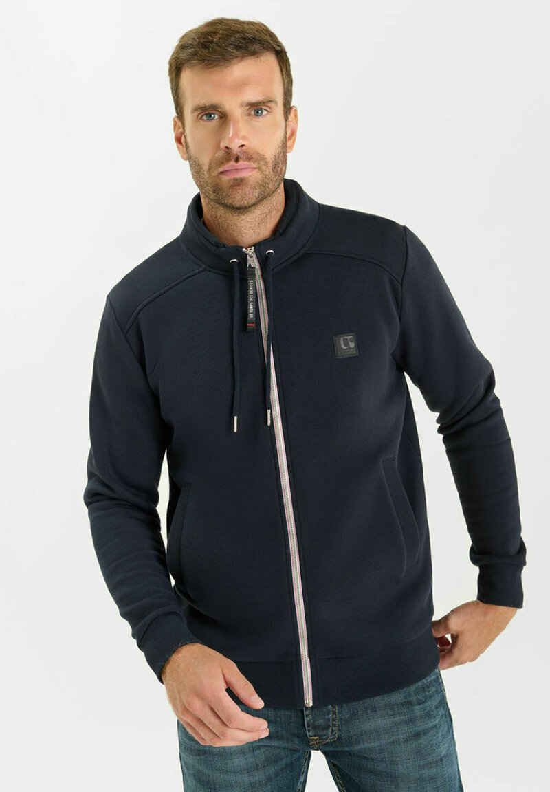 Felpa con zip color navy, colletto alto, tasche frontali e strisce bianche sullo zip; realizzata in un tessuto morbido e testurizzato.