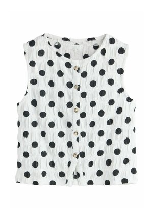 Hvid ærmeløs skjorte med knapper og sorte polkaprikker samt et tekstureret stofmønster.