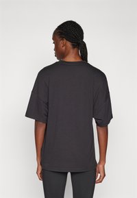 Svart oversized t-skjorte med korte ermer og rund utforming, laget av myk stoff. Enkelt design uten mønstre eller synlige detaljer.
