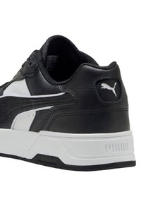 Sneaker Puma in bianco e nero che mostra i dettagli posteriori e laterali in pelle strutturata, logo Puma e suola spessa bianca.