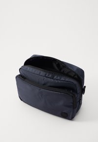 Navy blue zippered bag with a textured fabric, featuring one main compartment and a smaller front pocket, black zipper details.