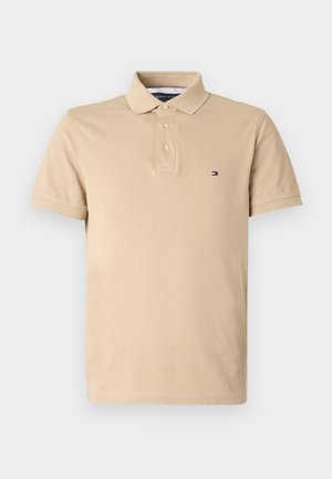 Beige poloshirt van katoen, met een klassieke kraag, een knoopsluiting met drie knopen en een klein logo op de linkerkant van de borst. Korte mouwen.